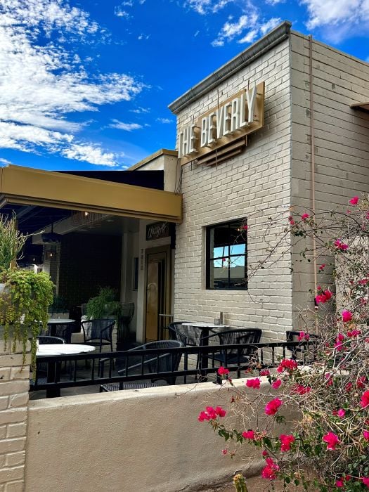 Charming exterior of The Beverly Cocktail Bar with outdoor seating and pink flowers in Scottsdale, Arizona.