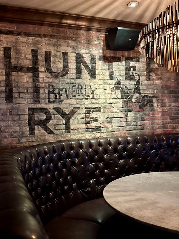 Cozy bar seating with brick wall and Hunt Beverly RYE sign in Scottsdale, Arizona.