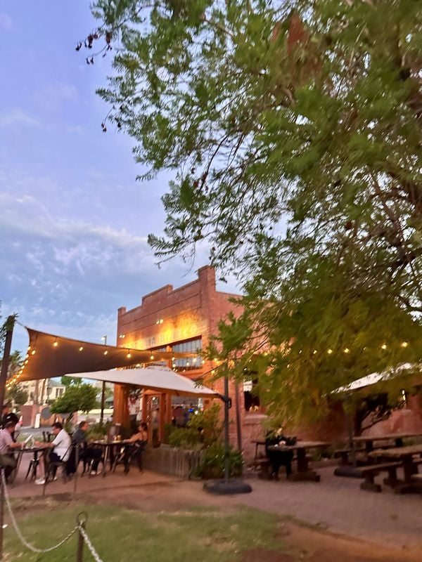 Outdoor dining area at the famous Pizzeria Bianco In Phoenix, with string lights and people enjoying evening.
