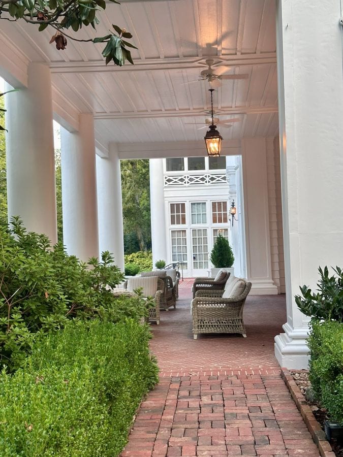 A view from the side, looking into the porch with hedges in the foreground at the Duke Mansion, one of the historic hotels in Chralotte.