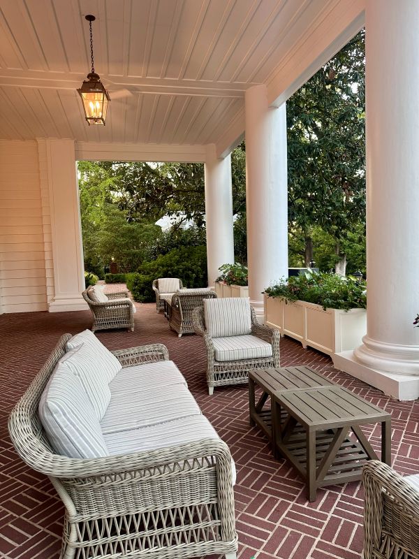 The side front porch with large white columns and whicker furniture at the Duke Mansion.