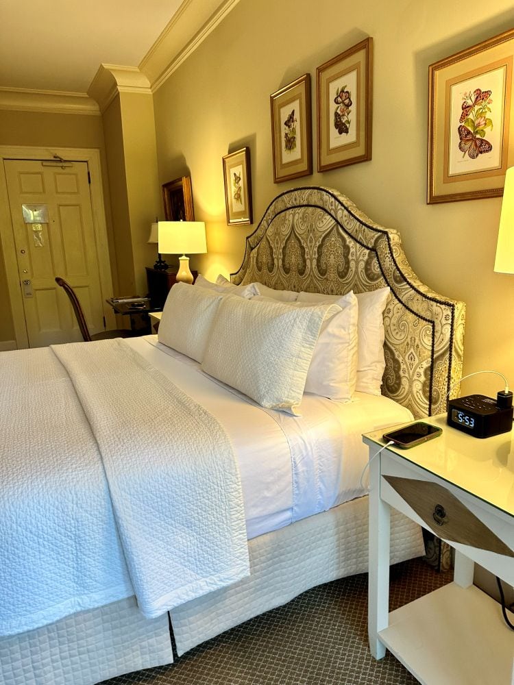 A guest bed with warm lighting off the enclosed second floor porch at the Duke Mansion, one of the historic hotels in Charlotte.