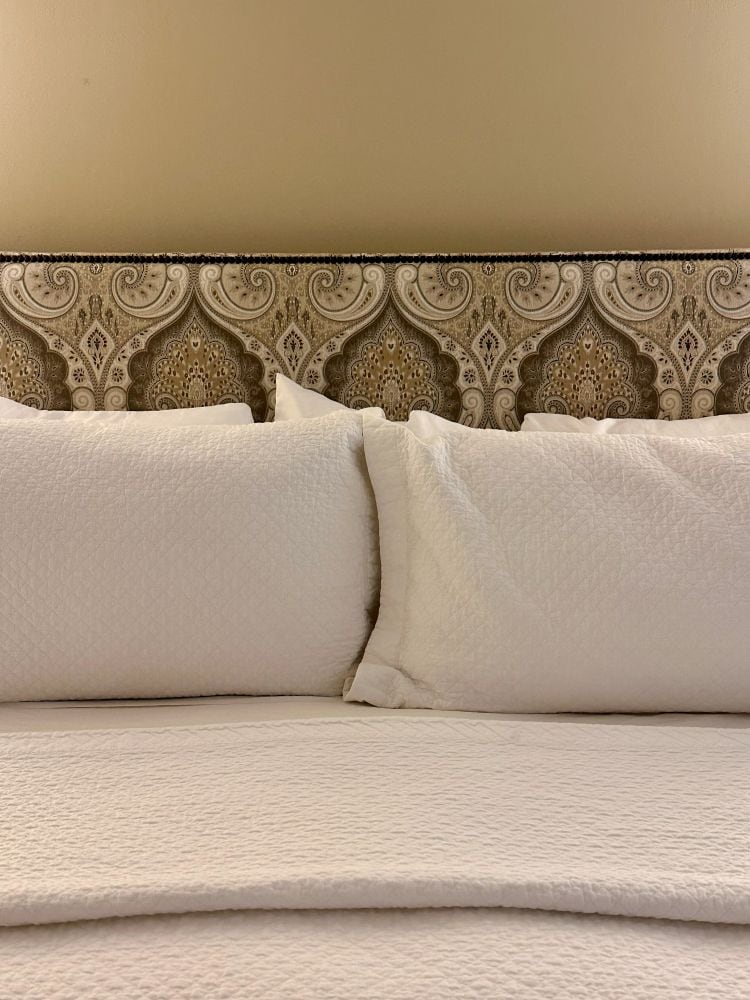 A close up of the pillows and headboard in a room at the Duke Mansion, one of the historic hotels in Charlotte.