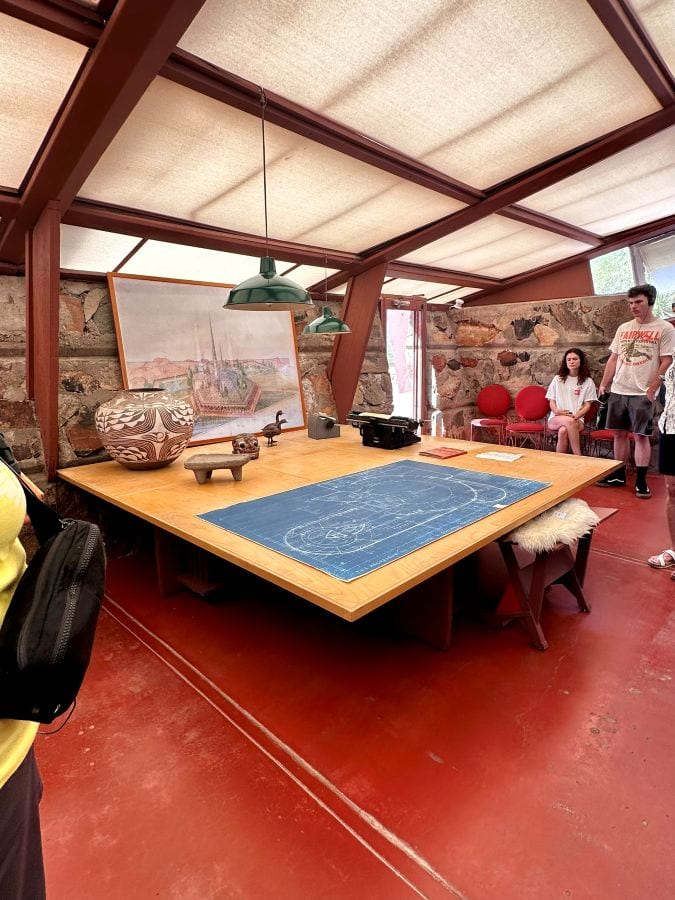 Indoor meeting room with large table, artwork, and stone wall in Taliesen West, a Frank Lloyd Wright home in Scottsdale, Arizona.