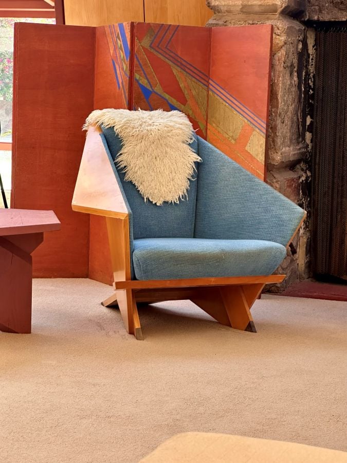 Modern blue armchair with wooden frame and sheepskin throw in Taliesen West, a Frank Lloyd Wright home in Scottsdale, Arizona.